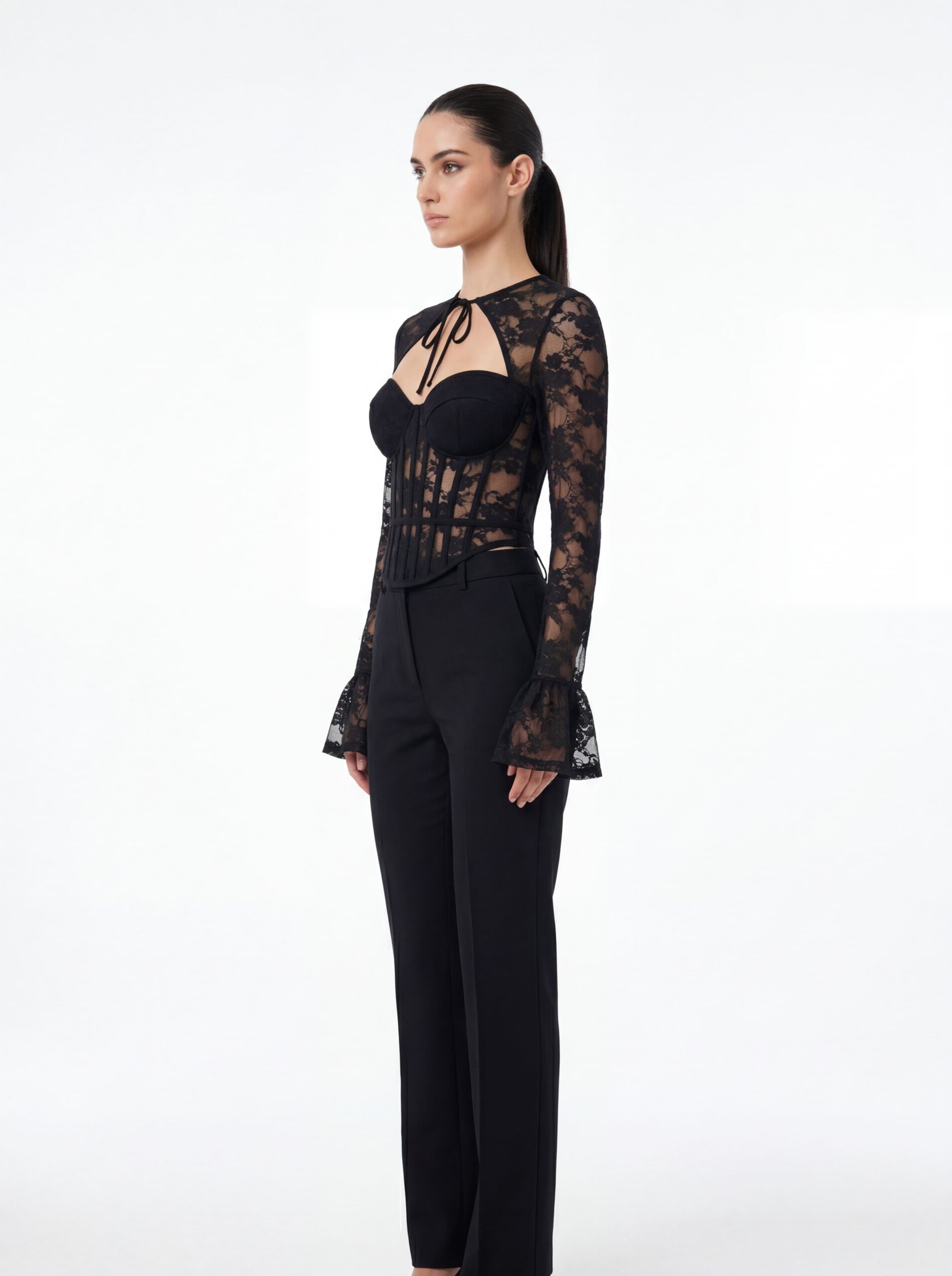 Three-quarter side shot of tie-neck black lace corset trouser outfit