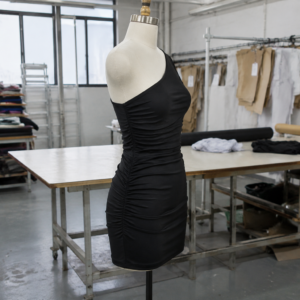 Infographic: Fabric property requirements for one shoulder dresses, listing stretch recovery (ASTM D3107), seam slippage (ASTM D434), shrinkage (AATCC 135), and strap elastic durability (ASTM D4964).